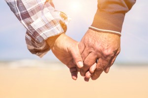 Senior couple in love walking at the beach holding hands in a ro